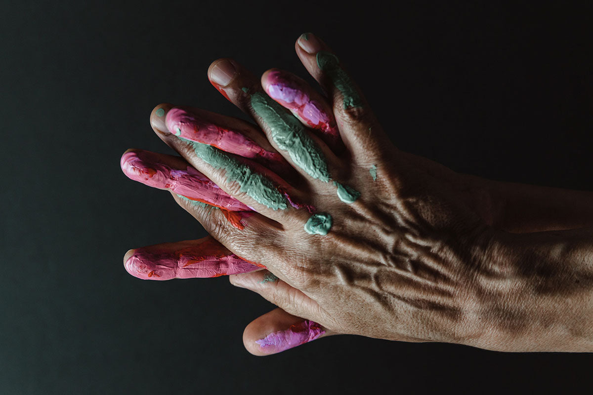 Hands With Paint On Them In Front Of a Black Bi