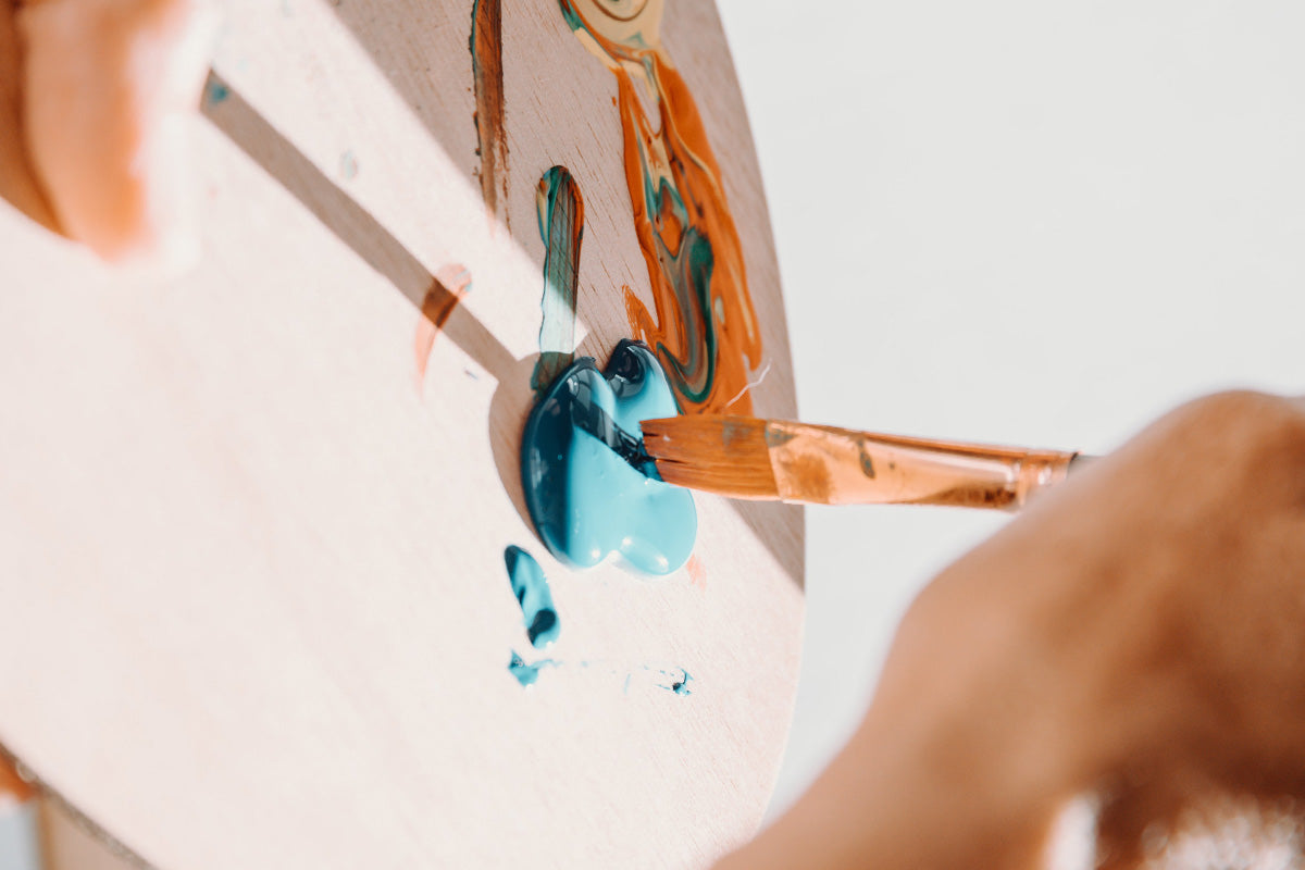 Hand dips paint brush into paint pallet