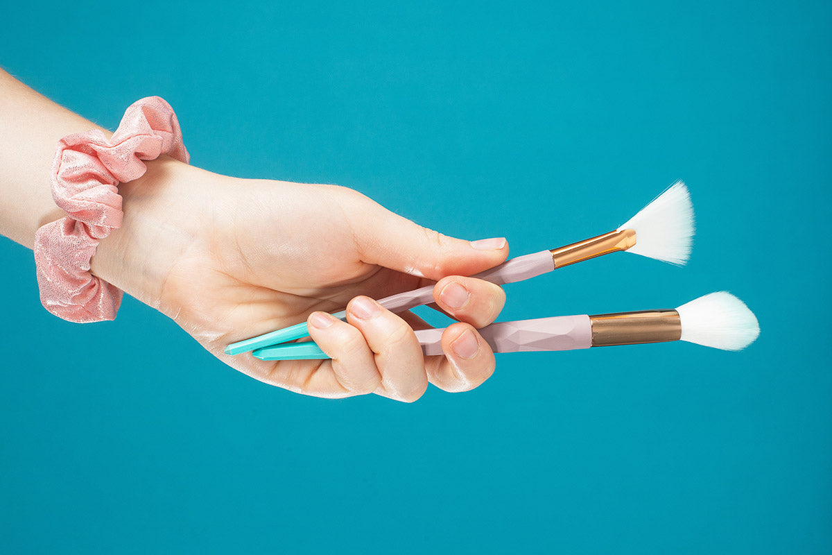 Hand holds two make up brushes up