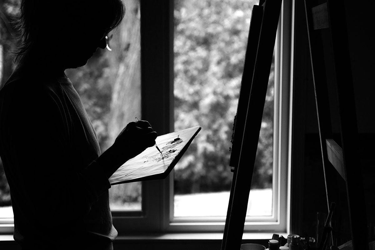 Monochrome photo of a person painting on an easel